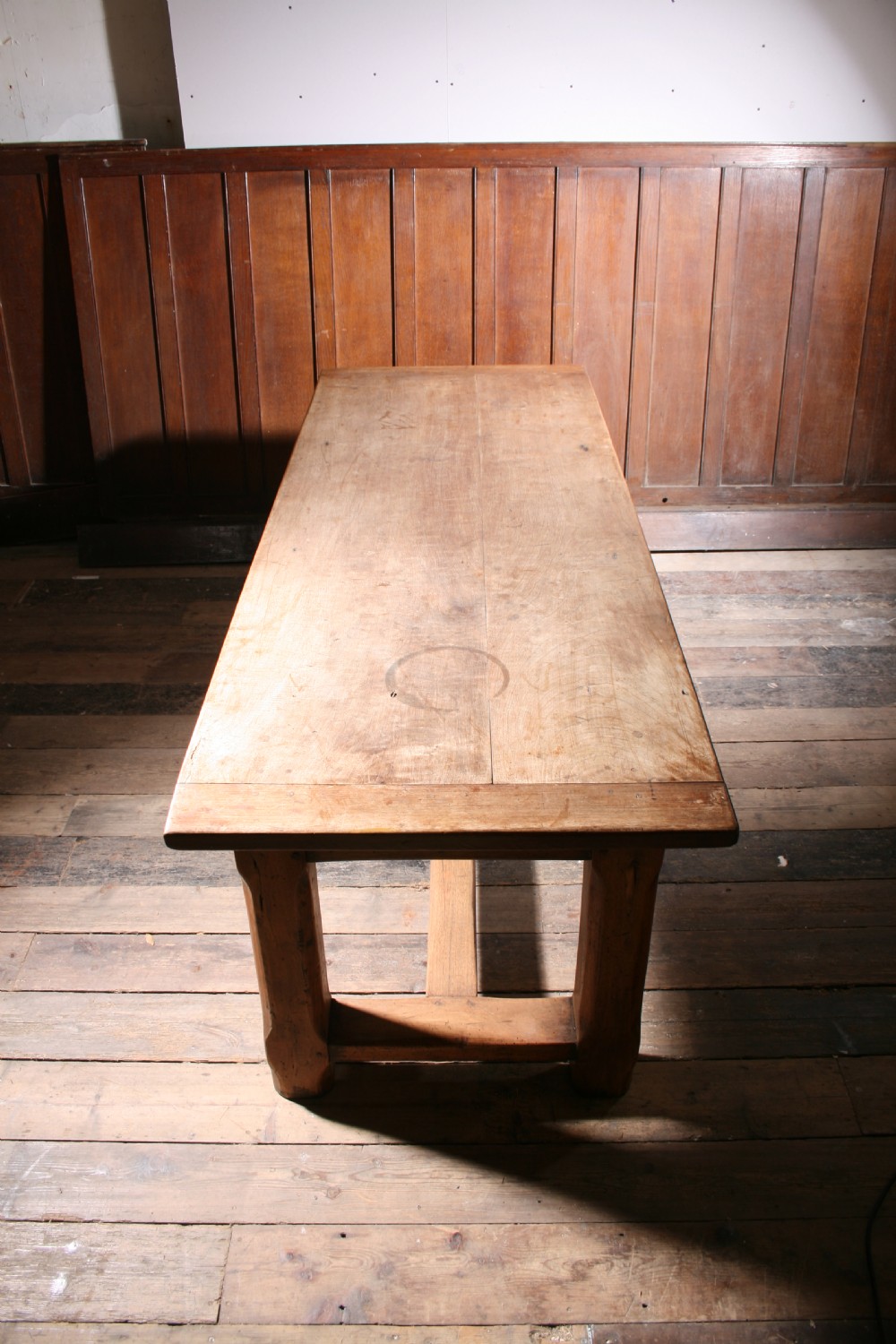 An antique walnut farmhouse dining table featuring a twin plank timber top, a single end drawer with a metal ring pull handle, and heavy legs connected by a central stretcher. View V