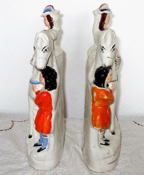 fig 1. A pair of antique glazed white earthenware figures depicting children in red dresses standing beside white horses on moulded bases.