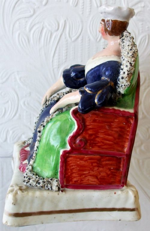 fig 1. A Victorian Staffordshire earthenware portrait figure depicting Queen Victoria seated on a throne in a cobalt blue dress.
