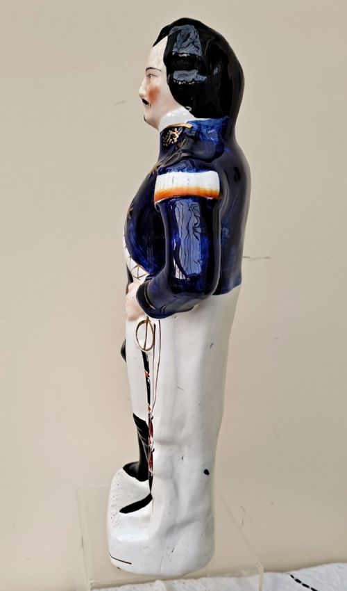 fig 1. A Victorian Staffordshire earthenware figure depicting Louis Napoleon III in a cobalt blue military tunic, white trousers, black boots, and carrying a bicorne hat.