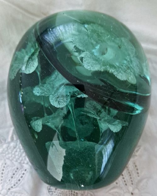 fig 1. A heavy ovoid dark green glass dump containing an internal encased floral design shaped like a pot of flowers.