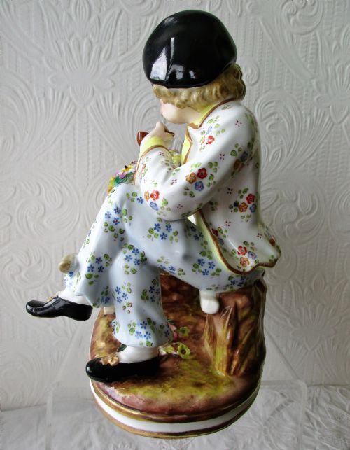fig 1. A Victorian hand-painted porcelain figurine depicting a seated flower seller with a wheelbarrow filled with hand-modelled blossoms.