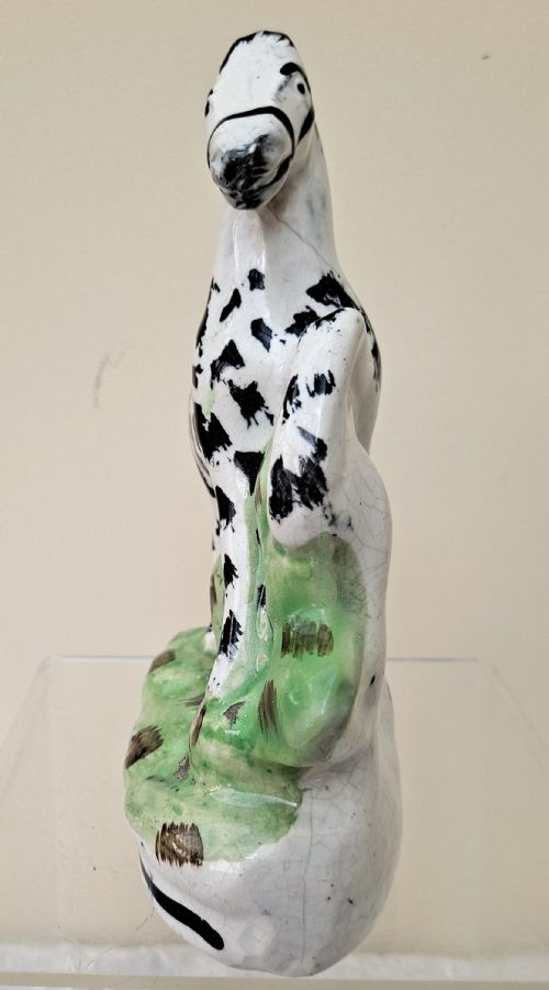 fig 1. A Victorian Staffordshire earthenware zebra figurine hand-painted with black stripes on a white body, standing on a green molded base.