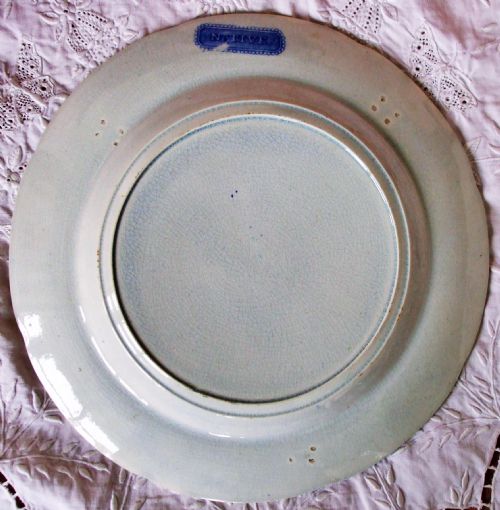 fig 1. An antique Georgian circular earthenware plate featuring a cobalt blue and white transfer printed landscape with figures and horses near a cottage, surrounded by a floral border.