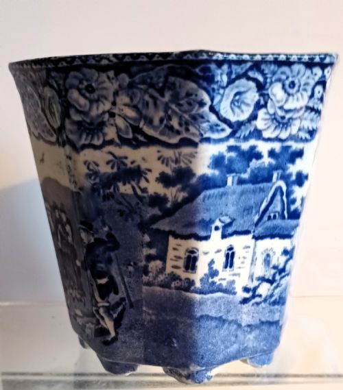 fig 1. An octagonal blue and white ceramic transferware cachepot featuring a rural landscape scene with horses and figures framed by a floral border.