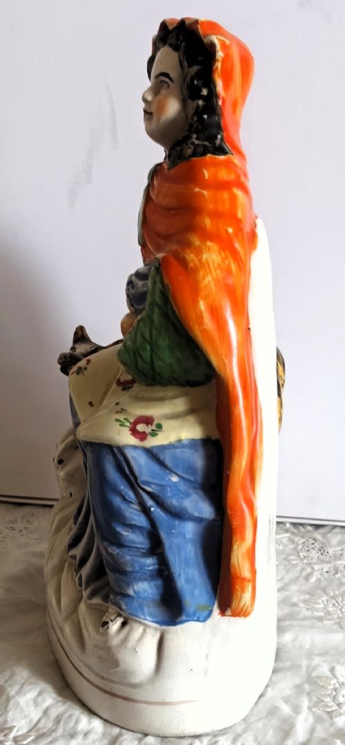 fig 1. A Victorian Staffordshire earthenware pottery figure depicting Little Red Riding Hood wearing an orange hood with a basket and a wolf at her side.