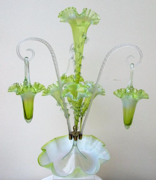 fig 1. A Victorian vaseline glass epergne featuring a central ruffled trumpet vase, surrounding horns, hanging baskets, and a bowl base in yellow-green opalescent glass.