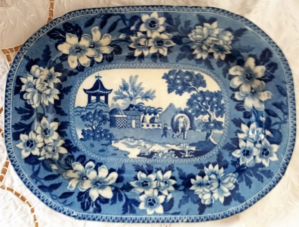 An oval Georgian blue and white ceramic platter decorated with a Chinoiserie scene featuring an elephant, framed by a broad floral border.