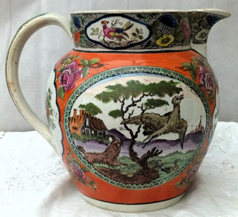 An antique Georgian pearlware Dutch jug featuring a bright orange ground and decorative oval medallions depicting hand-painted polychrome birds and foliage. View III