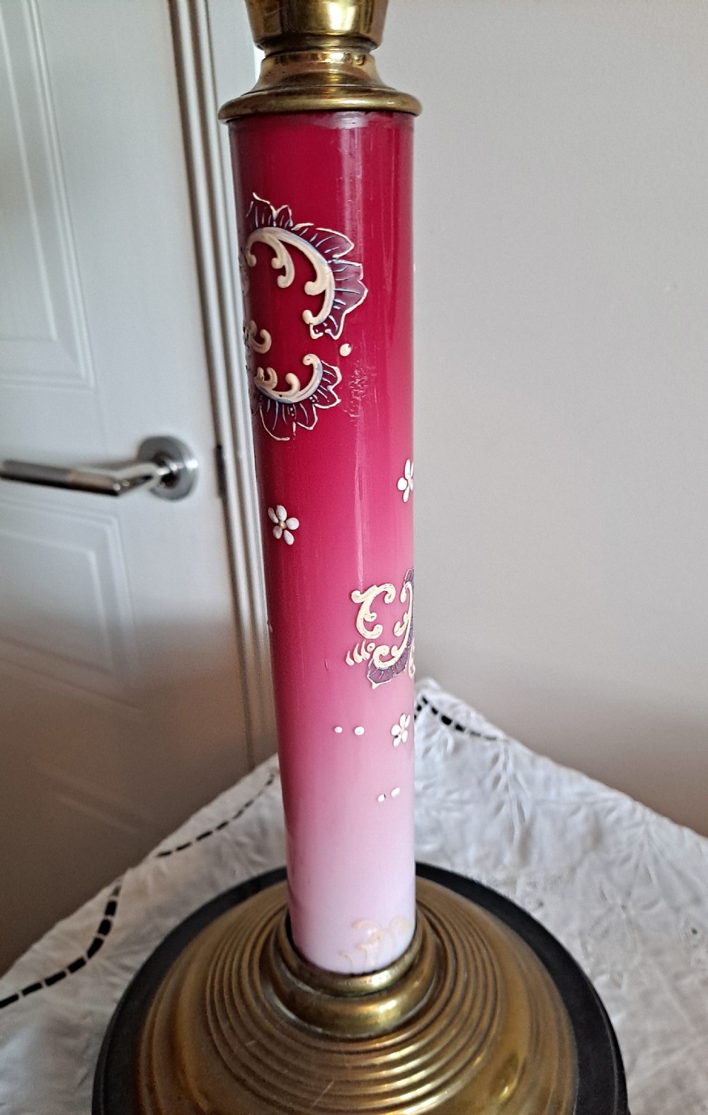 A Victorian column oil lamp featuring a cranberry pink etched glass shade, a matching pink glass reservoir, and a brass column on a black circular base. View VII