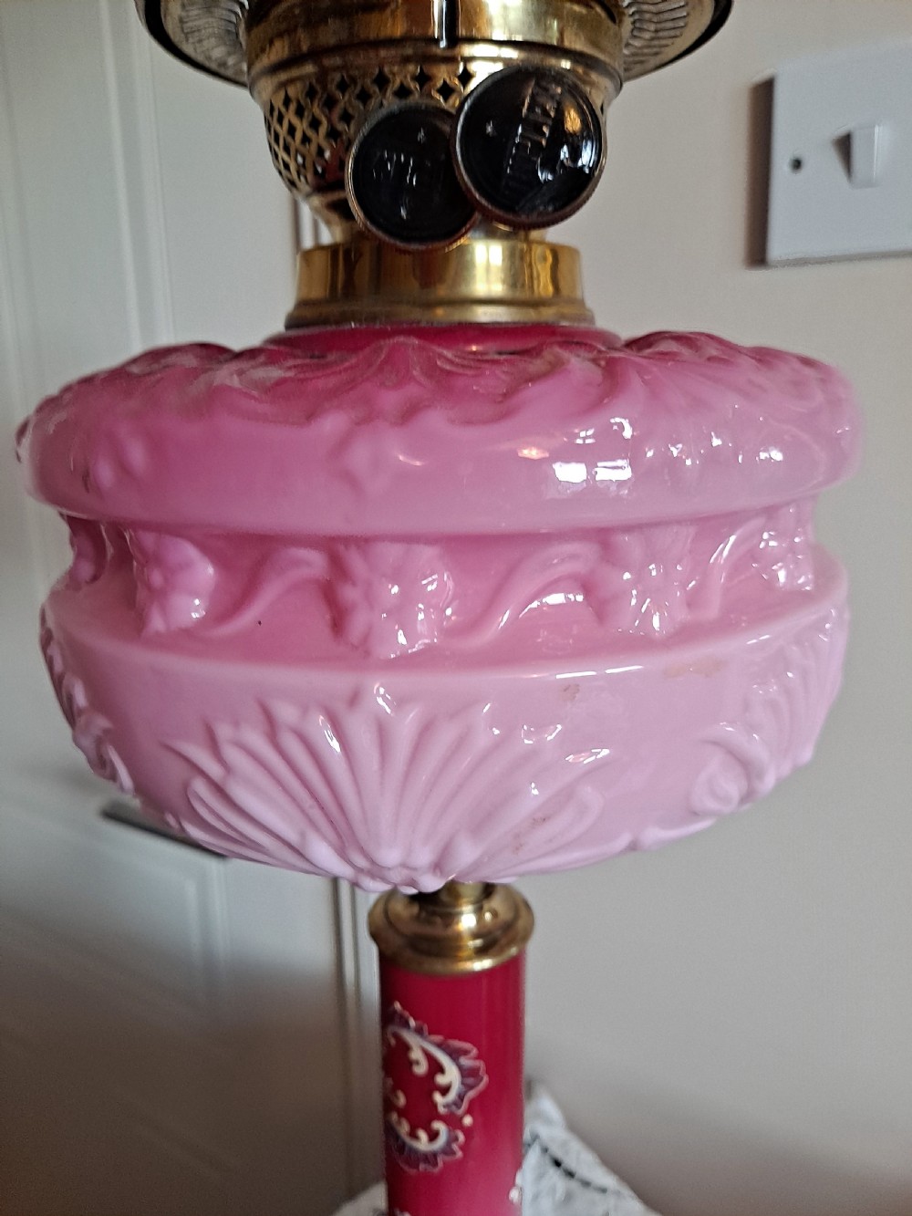 A Victorian column oil lamp featuring a cranberry pink etched glass shade, a matching pink glass reservoir, and a brass column on a black circular base. View VIII
