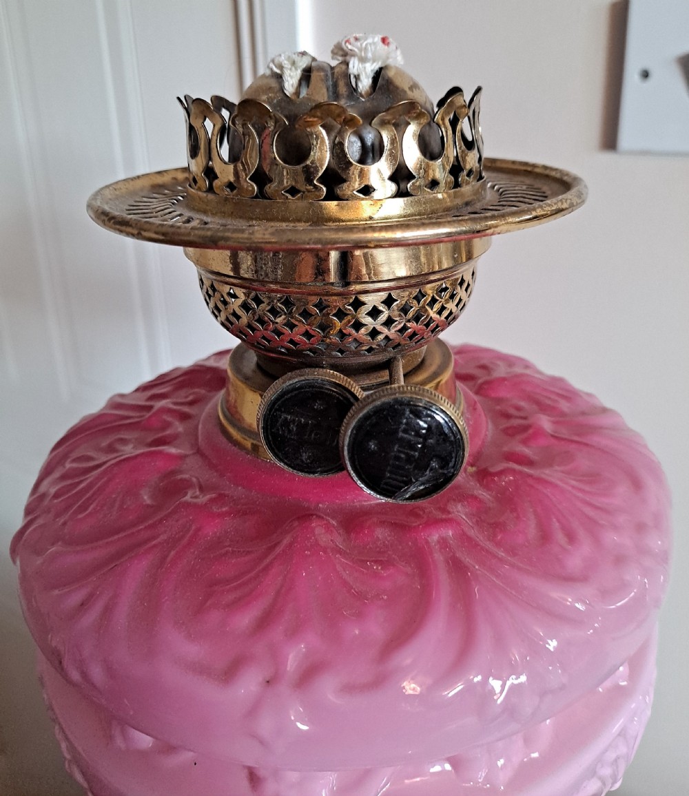 A Victorian column oil lamp featuring a cranberry pink etched glass shade, a matching pink glass reservoir, and a brass column on a black circular base. View IX