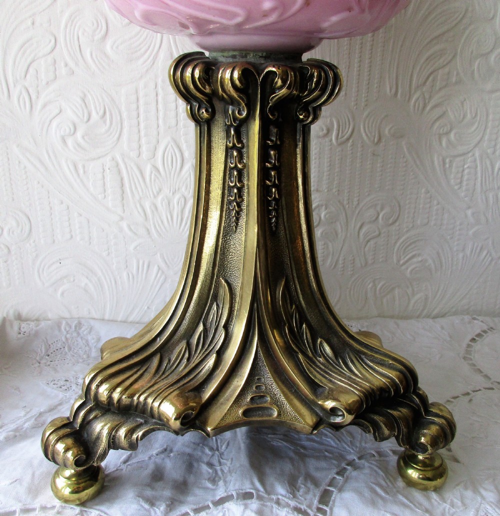 A Victorian oil lamp with a cast brass scrolled base, a pink moulded glass font, and a cranberry frilled glass shade. View II