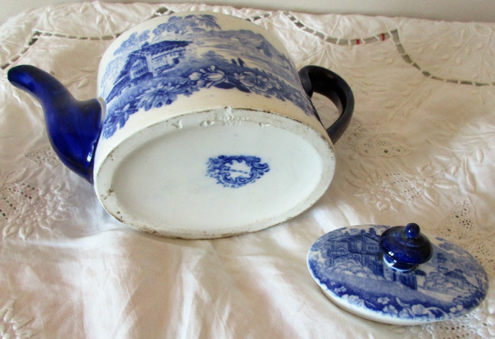 A Victorian Mintons solitaire porcelain teapot displaying a blue and white Genevese transferware landscape pattern with a cobalt blue handle, spout, and finial. View V