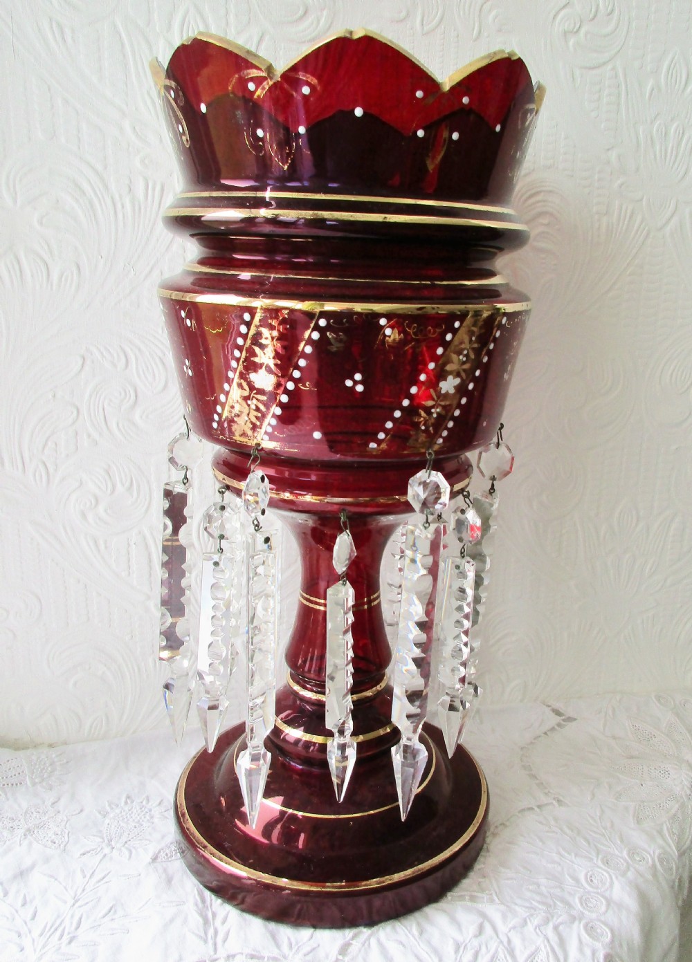 A pair of deep ruby red glass Victorian lustres featuring scalloped upper rims, hand-painted gold foliage, and suspended clear cut-crystal prisms. View II