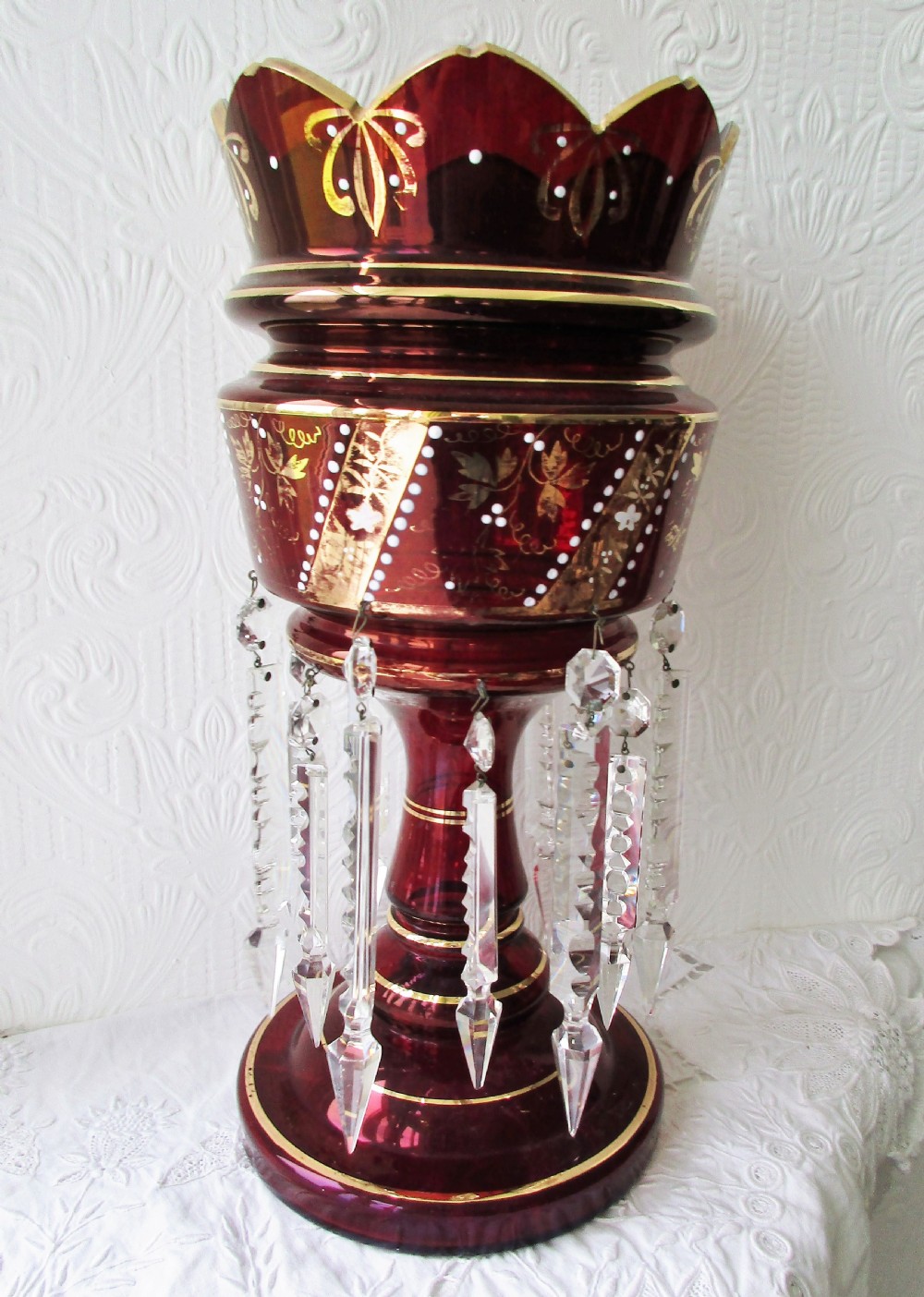A pair of deep ruby red glass Victorian lustres featuring scalloped upper rims, hand-painted gold foliage, and suspended clear cut-crystal prisms. View III