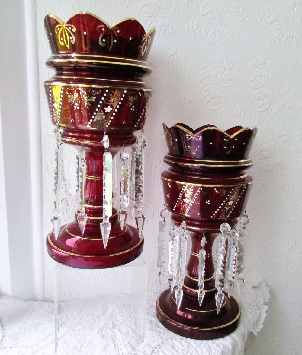 A pair of deep ruby red glass Victorian lustres featuring scalloped upper rims, hand-painted gold foliage, and suspended clear cut-crystal prisms. View V