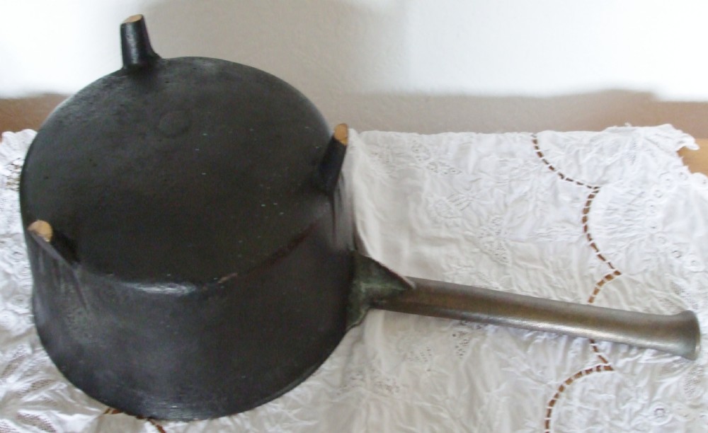 An antique Georgian cast bronze posnet skillet featuring three short tripod legs, a polished metal interior, and a long flat handle. View V