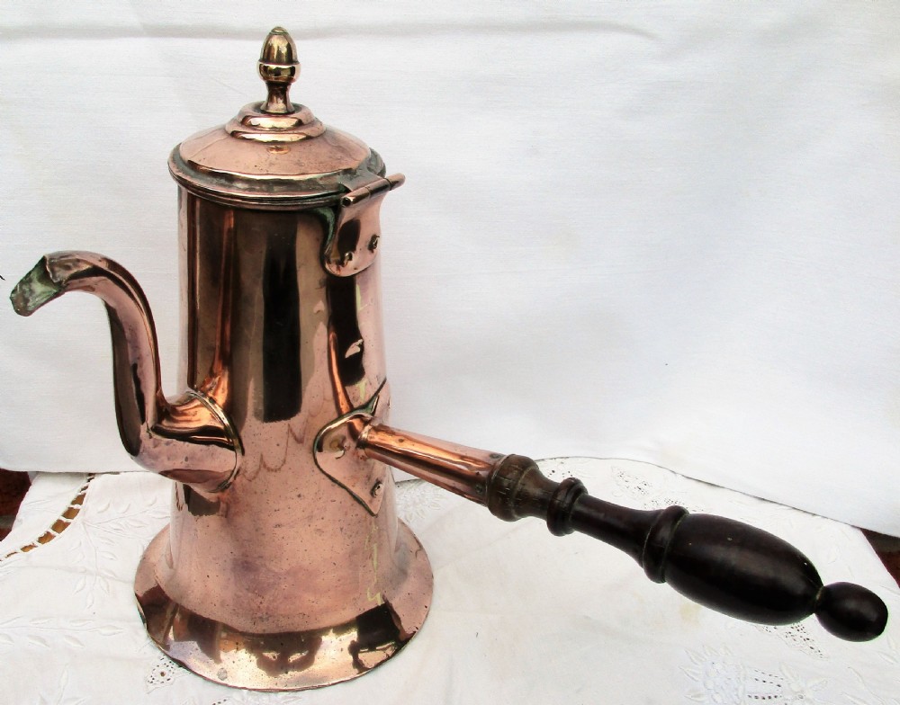 An antique Georgian copper coffee pot featuring a curved goose-neck spout, a hinged lid with a brass finial, and a turned dark wood side handle.