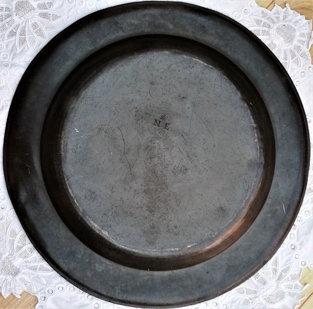 A round Georgian pewter charger dish featuring a broad rim, a shallow central basin, and a dark oxidised patina. View II