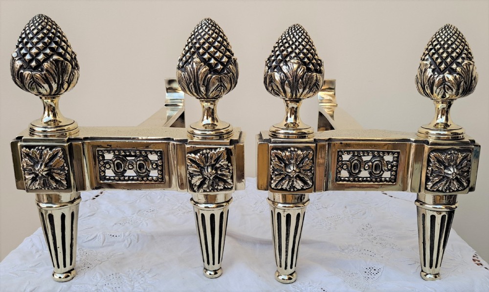 A pair of polished Georgian brass andirons with pineapple finials, rosette panels, and fluted legs.