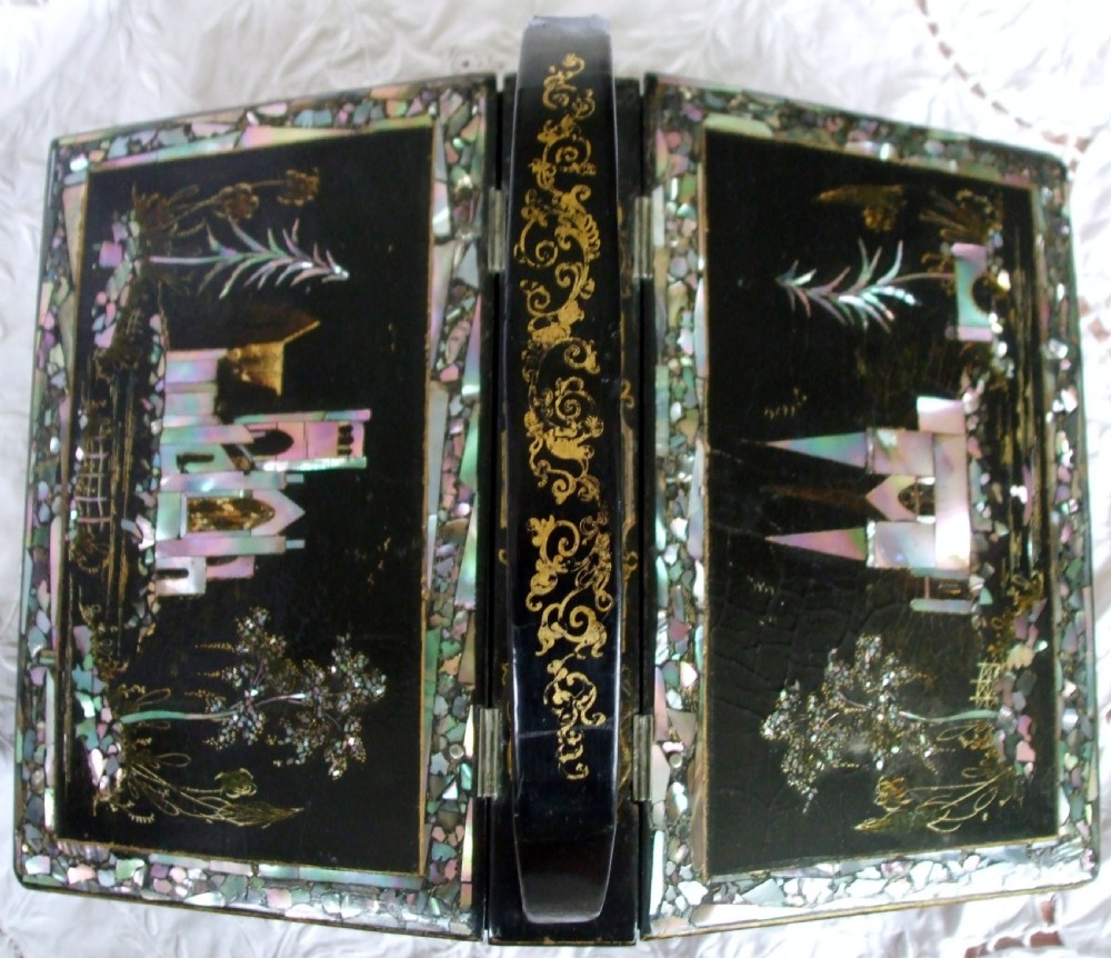 A Victorian black lacquered papier-mache needlework casket featuring mother-of-pearl inlay, gilded foliate patterns, and an overhead carrying handle. View II