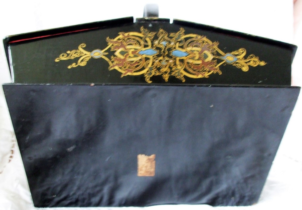 A Victorian black lacquered papier-mache needlework casket featuring mother-of-pearl inlay, gilded foliate patterns, and an overhead carrying handle. View VI