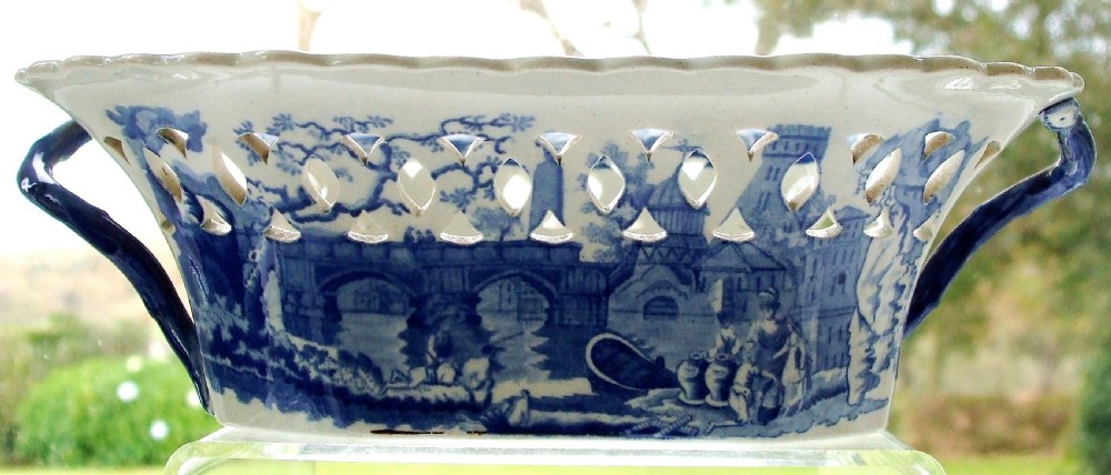 An antique oval blue and white earthenware chestnut basket featuring pierced openwork sides and a central printed river landscape scene. View III