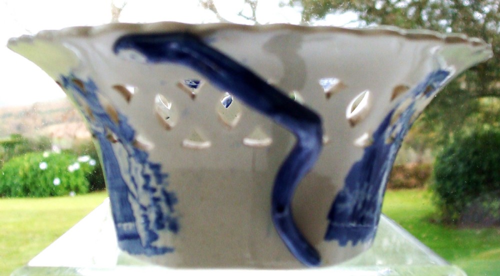 An antique oval blue and white earthenware chestnut basket featuring pierced openwork sides and a central printed river landscape scene. View VII