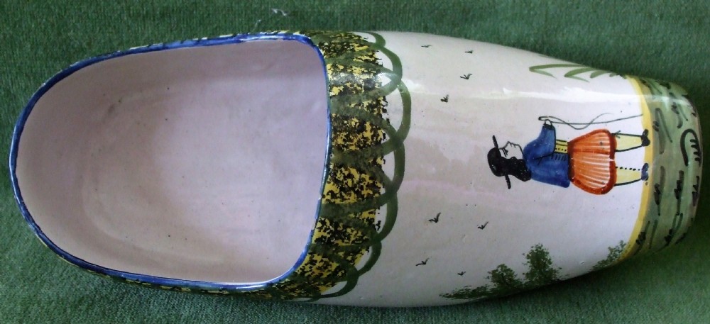 An off-white tin-glazed earthenware sabot featuring a hand-painted Breton figure and decorative patterned borders.