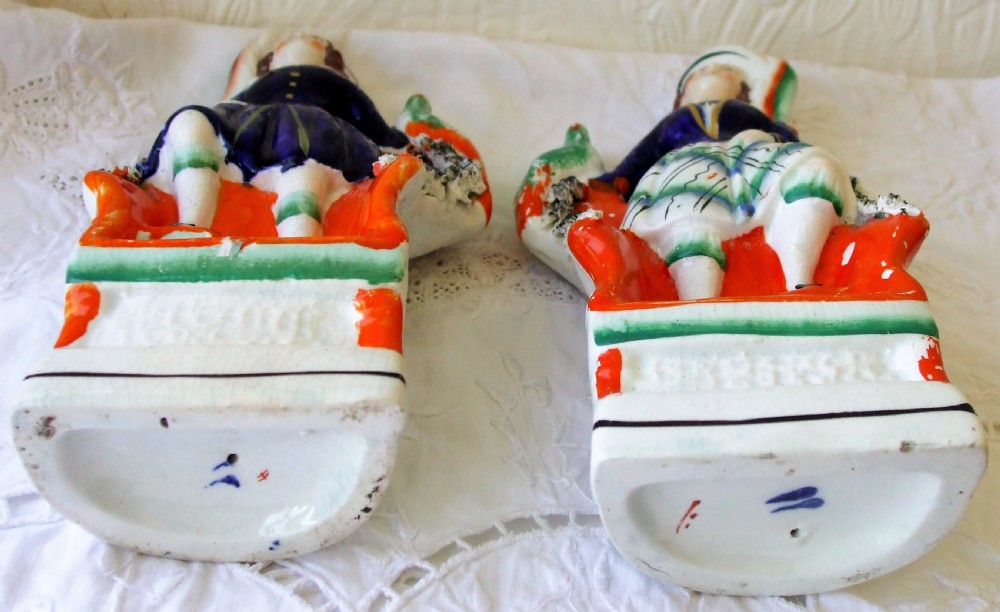 A pair of Victorian hand-painted Staffordshire earthenware figures depicting royal children seated on orange chairs with green birds. View V