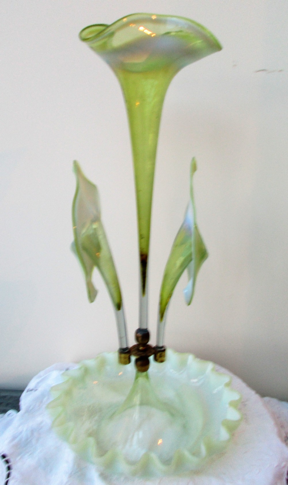 A Victorian Art Nouveau translucent green glass epergne featuring a ruffled base bowl and two fluted lily-form glass trumpets joined by a metal collar. View II