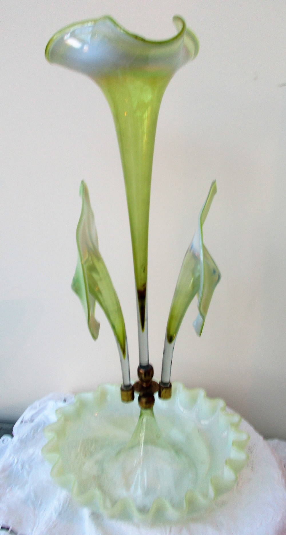 A Victorian Art Nouveau translucent green glass epergne featuring a ruffled base bowl and two fluted lily-form glass trumpets joined by a metal collar. View V