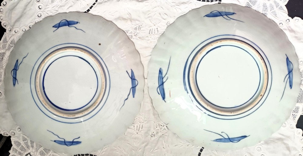 A pair of circular Japanese Meiji period Imari porcelain dishes featuring scalloped edges and detailed blue and red floral patterns. View VI