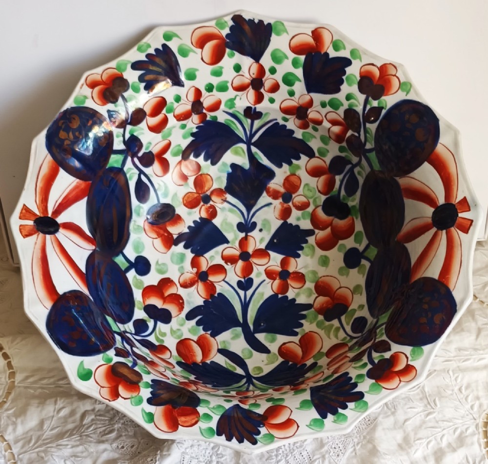 An octagonal Victorian ceramic toilet basin featuring hand-painted Gaudy Welsh Celyn pattern floral designs in cobalt blue, rust red, and green with copper lustre detailing on a white glaze.