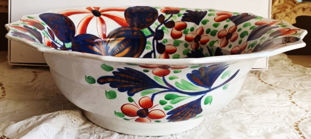 An octagonal Victorian ceramic toilet basin featuring hand-painted Gaudy Welsh Celyn pattern floral designs in cobalt blue, rust red, and green with copper lustre detailing on a white glaze. View V