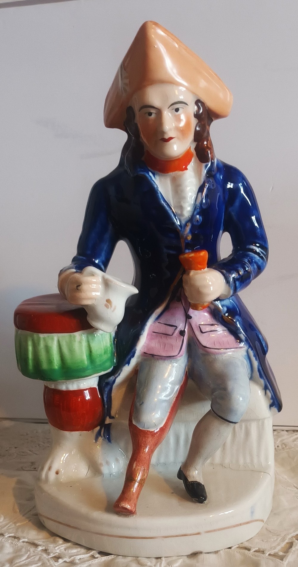 A Victorian Staffordshire earthenware ceramic figure depicting a seated sailor with a peg leg wearing a blue coat and tricorn hat.