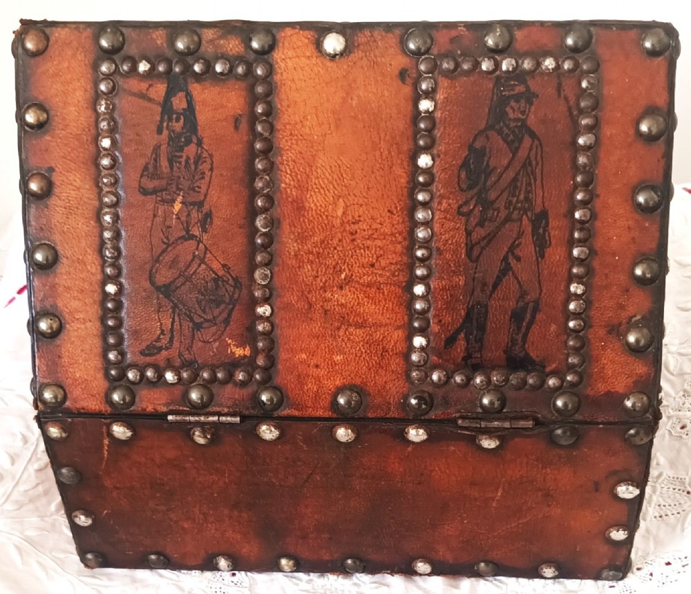 A rectangular Georgian leather-bound casket decorated with brass studs, etched military figure illustrations, and a central iron latch. View V
