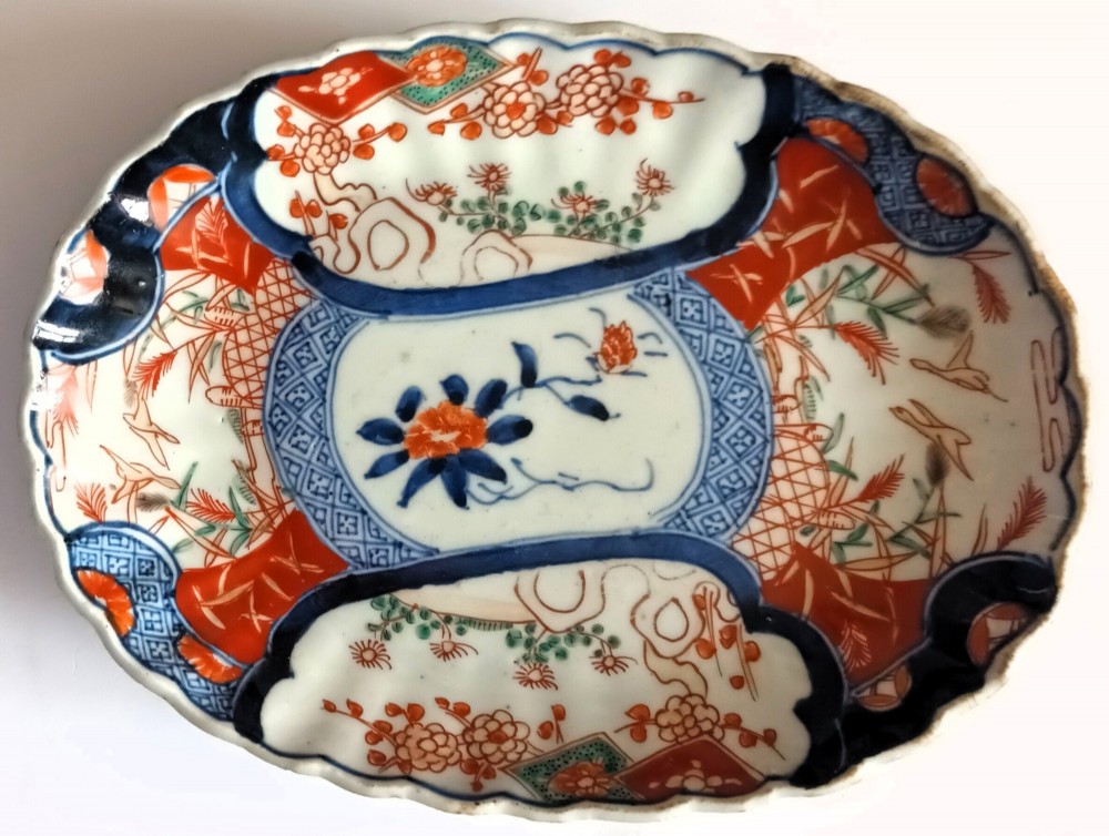A pair of oval antique Japanese Imari porcelain dishes with scalloped rims, featuring hand-painted floral and bird motifs in cobalt blue, iron red, and white enamels. View III