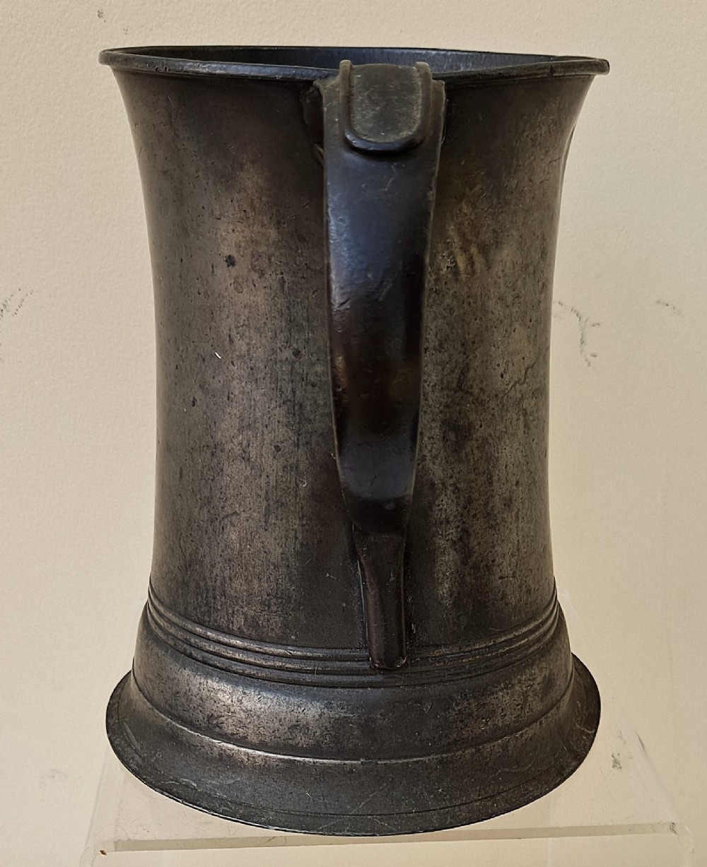 An antique Victorian pewter quart mug featuring a concave waist, flared base with moulded trim, and a dark curved loop handle. View II