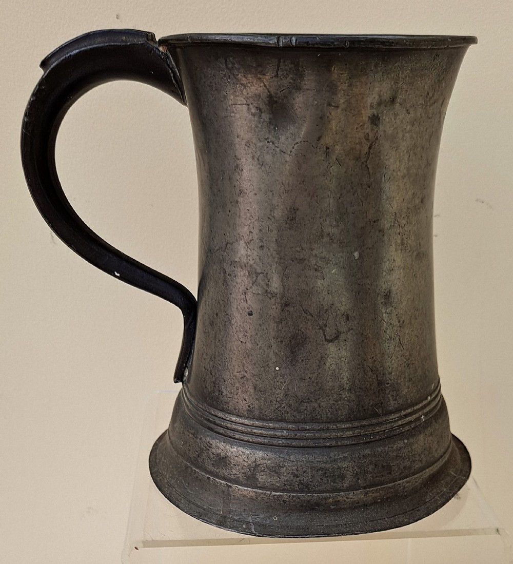 An antique Victorian pewter quart mug featuring a concave waist, flared base with moulded trim, and a dark curved loop handle. View III