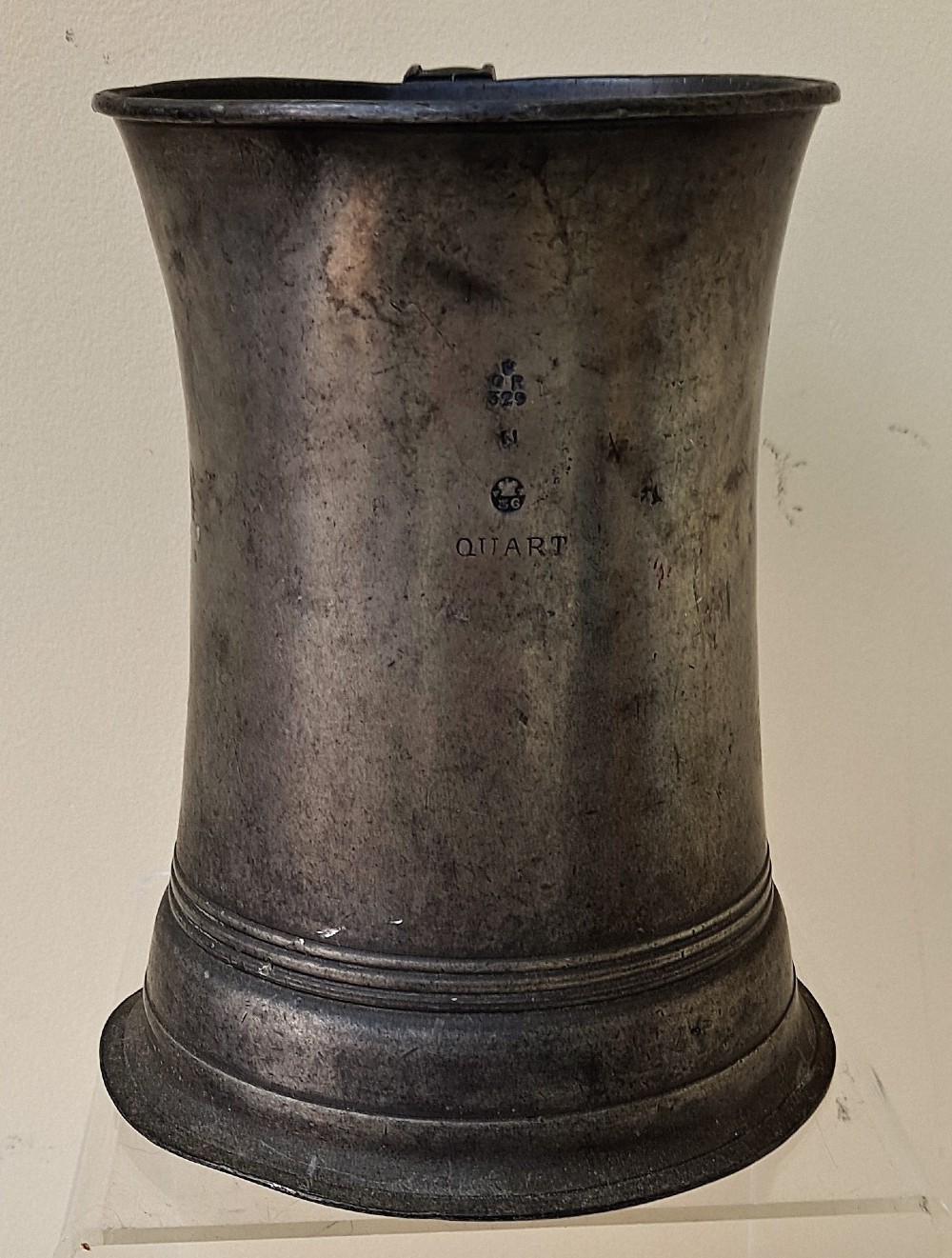 An antique Victorian pewter quart mug featuring a concave waist, flared base with moulded trim, and a dark curved loop handle. View IV