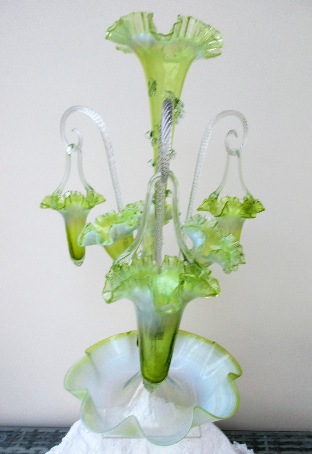A Victorian vaseline glass epergne featuring a central ruffled trumpet vase, surrounding horns, hanging baskets, and a bowl base in yellow-green opalescent glass. View III