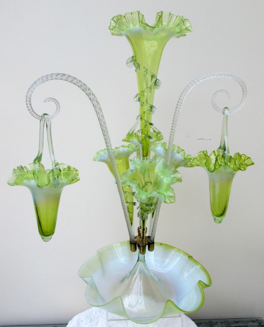 A Victorian vaseline glass epergne featuring a central ruffled trumpet vase, surrounding horns, hanging baskets, and a bowl base in yellow-green opalescent glass. View IV
