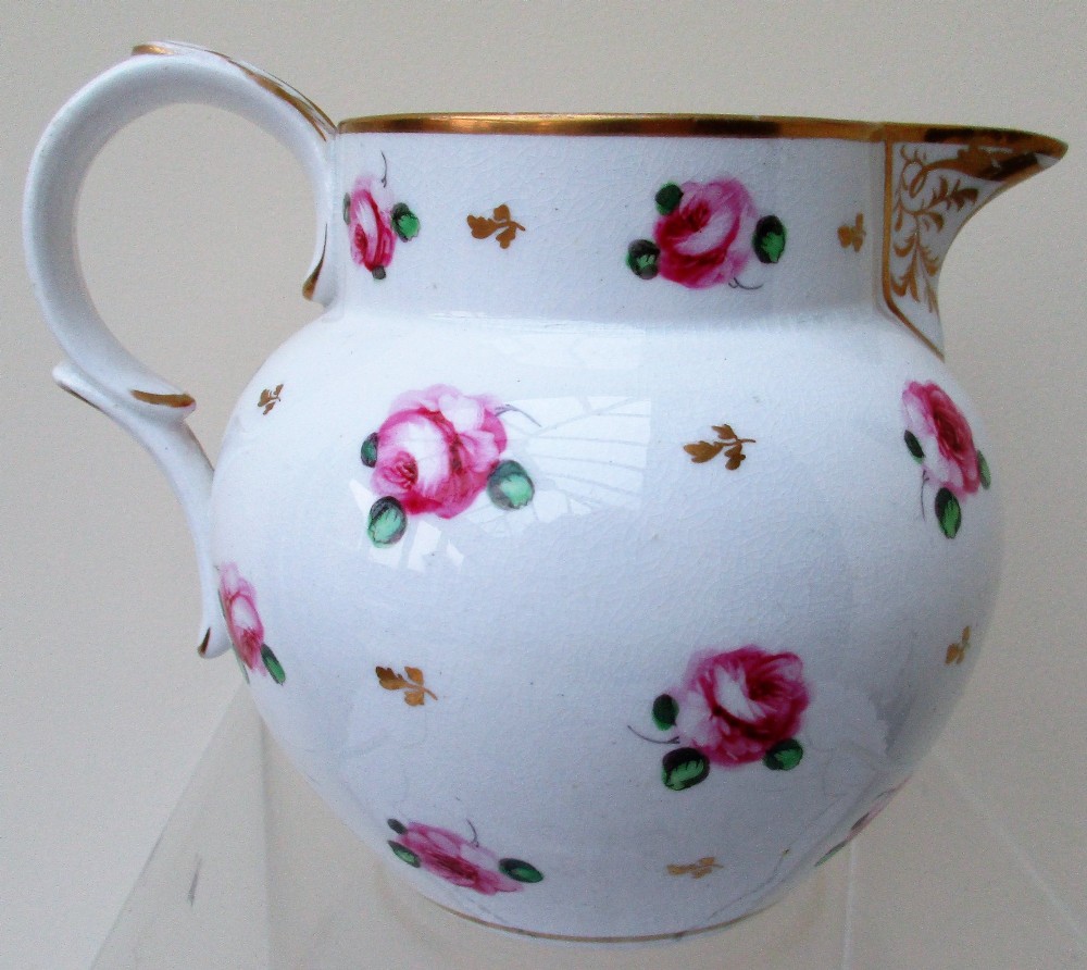 An antique white porcelain cream jug featuring hand-painted pink rose sprigs, gold leaf detailing, a pointed sparrow beak spout, and a curved handle. View III