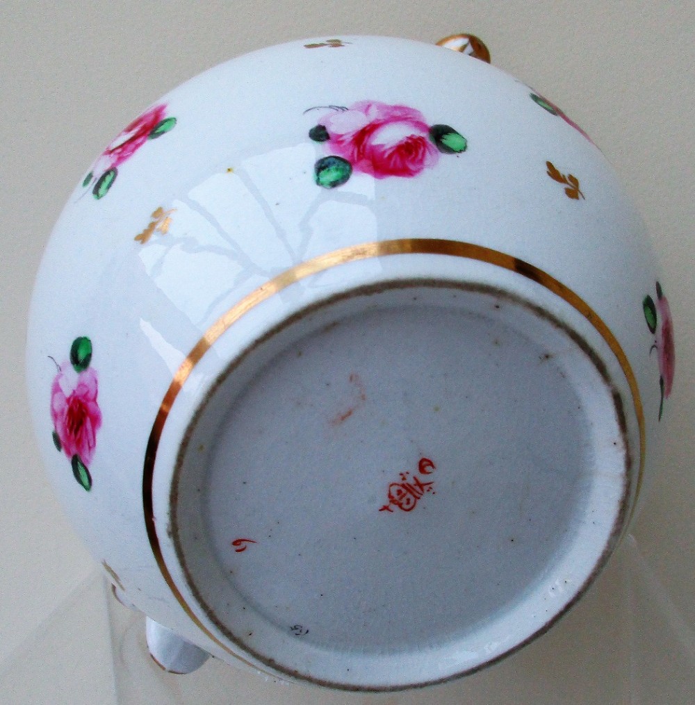 An antique white porcelain cream jug featuring hand-painted pink rose sprigs, gold leaf detailing, a pointed sparrow beak spout, and a curved handle. View V