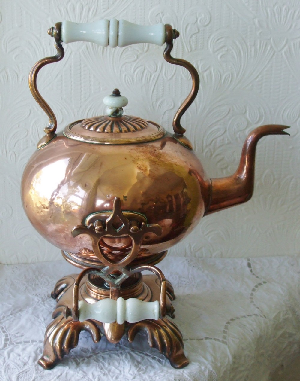 An antique Victorian copper spirit kettle featuring a white ceramic handle, gooseneck spout, and decorative brass stand with burner. View III