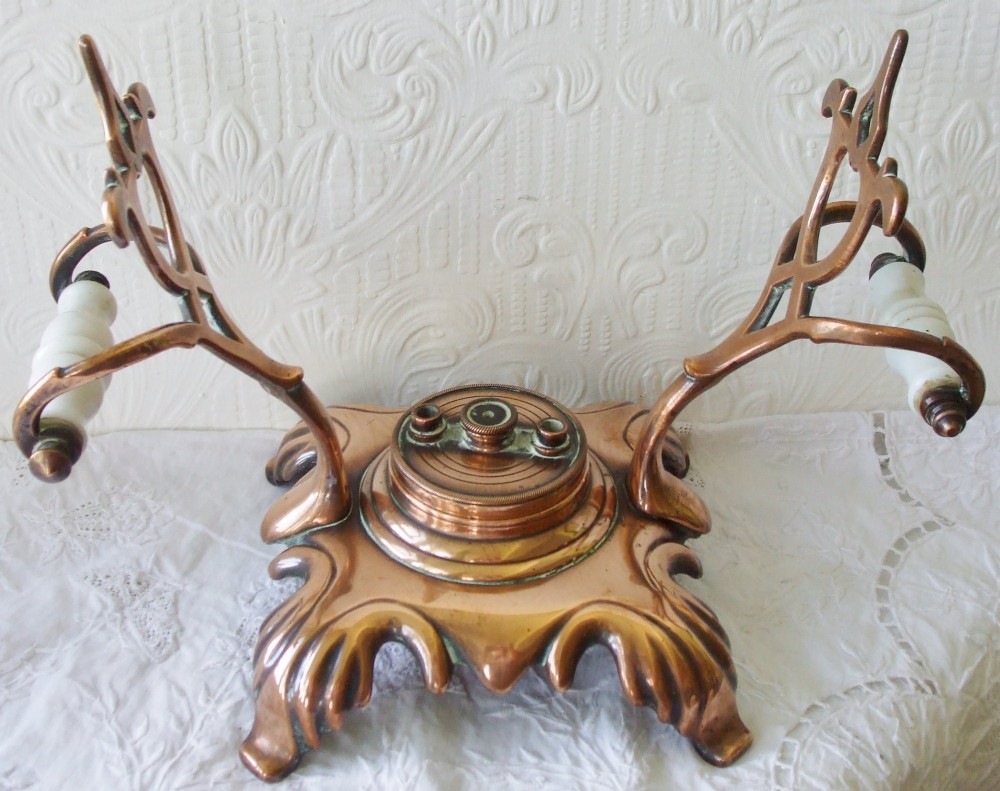 An antique Victorian copper spirit kettle featuring a white ceramic handle, gooseneck spout, and decorative brass stand with burner. View VII