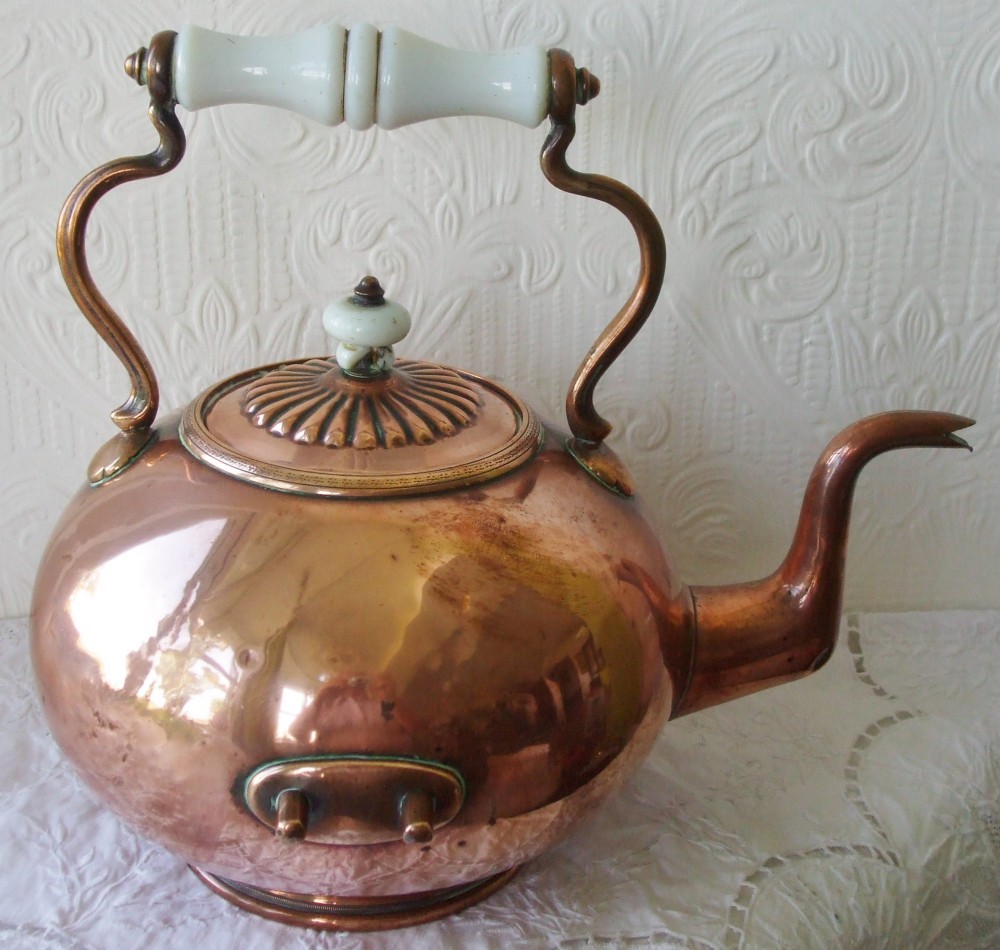 An antique Victorian copper spirit kettle featuring a white ceramic handle, gooseneck spout, and decorative brass stand with burner. View X