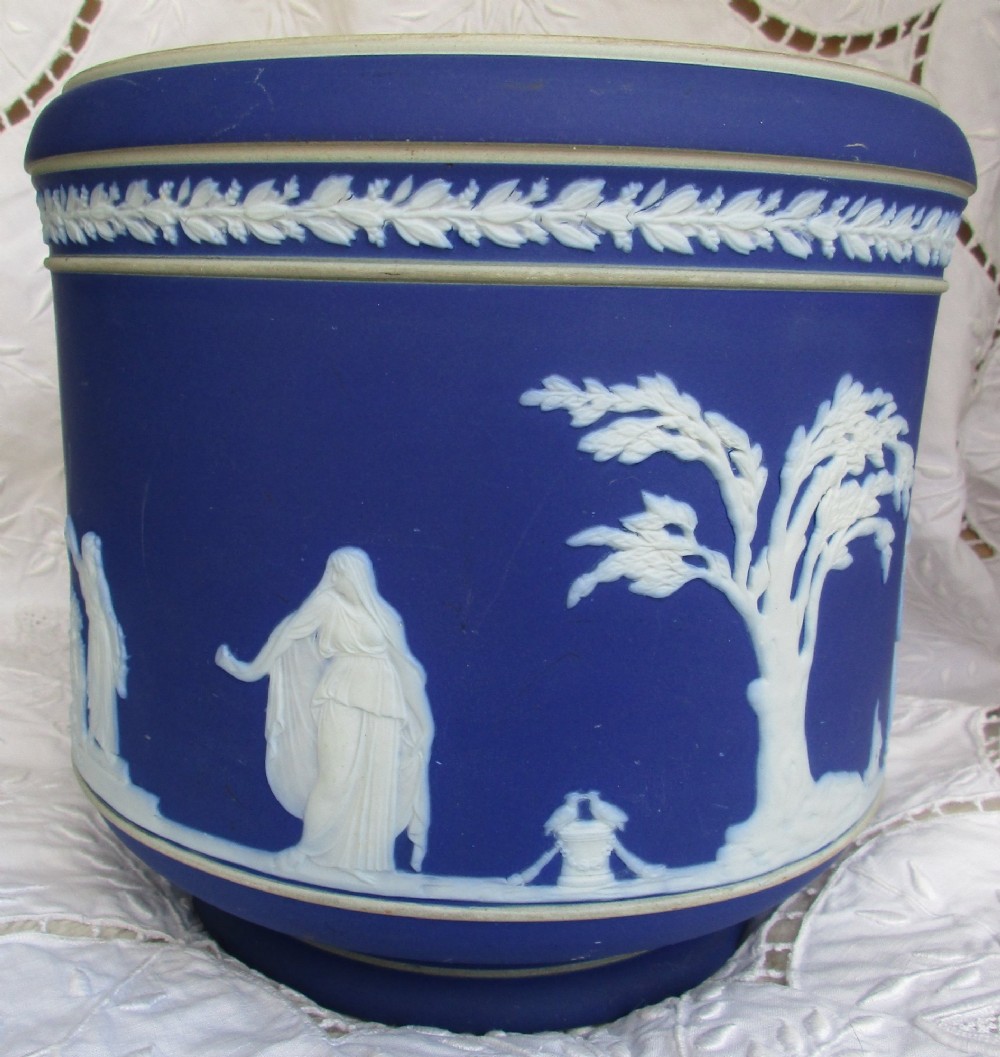 A deep cobalt blue Victorian jasperware ceramic jardiniere decorated with white classical relief figures, trees, and a foliate rim border. View III